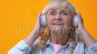 戴着白色耳机听音乐、欣赏最喜<strong>爱的旋律的</strong>老年妇女